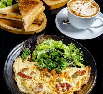 fried eggs with mushrooms served with greens sandwiches and cup of coffee